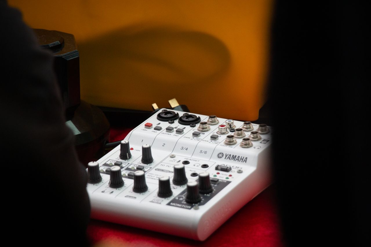 Detailed view of a Yamaha audio mixer with knobs and inputs in a studio setting.
