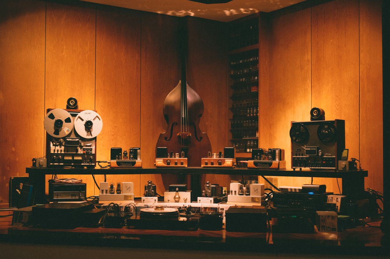 about-us-02 A retro-themed room featuring vintage audio equipment and a double bass. Perfect for music lovers.
