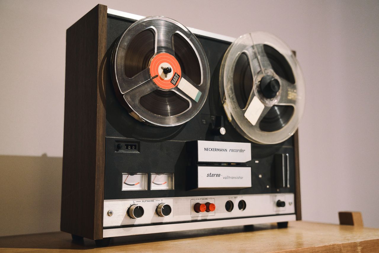 summer-sale Close-up of a classic reel-to-reel tape recorder on a wooden surface, showcasing audio nostalgia.
